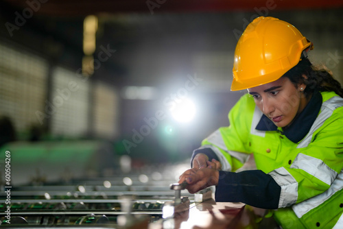 Factory engineer Brazilian woman checking and reparing mahine at heavy factory.Worker works at heavy machine at industry factory. with machinery equipment plant technology. photo