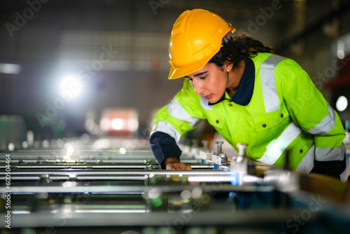 Factory engineer Brazilian woman checking and reparing mahine at heavy factory.Worker works at heavy machine at industry factory. with machinery equipment plant technology. photo