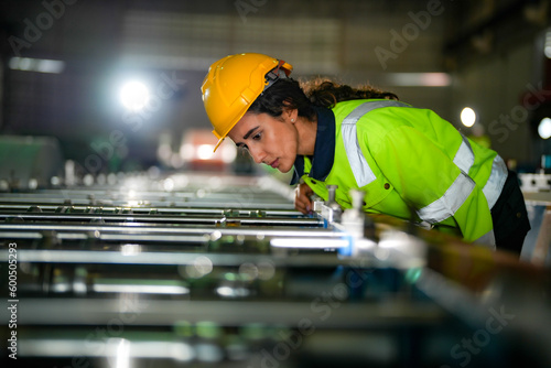 Factory engineer Brazilian woman checking and reparing mahine at heavy factory.Worker works at heavy machine at industry factory. with machinery equipment plant technology. photo