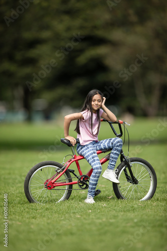girl posing with a bicycle in the park on a sunny day