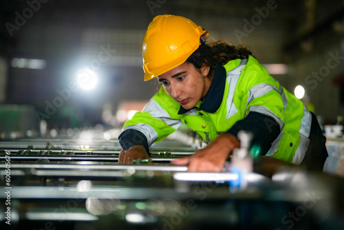 Factory engineer Brazilian woman checking and reparing mahine at heavy factory.Worker works at heavy machine at industry factory. with machinery equipment plant technology. photo