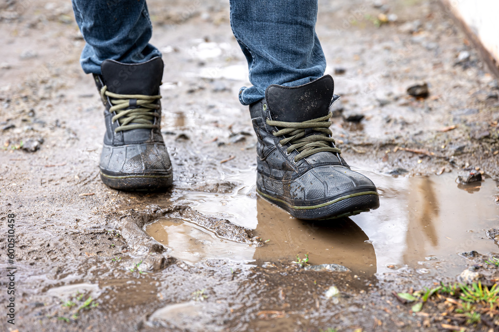 A man in jeans and boots walks through the swamp in rainy weather. A man in jeans and boots walks through the swamp in rainy weather.