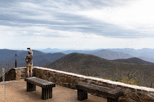 Young man taking a picture of the Blue Ridge Mountains from the top of Brasstown Bald photo