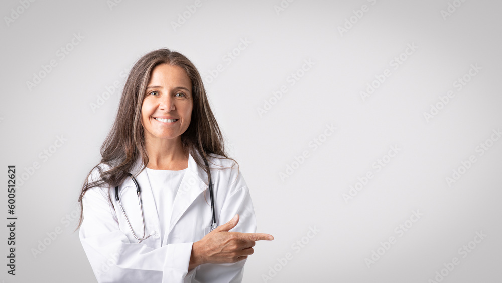 Useful medical information. Portrait of confident senior woman doc pointing aside at copy space over light background Useful medical information. Portrait of confident senior woman doc pointing aside at copy space over light background