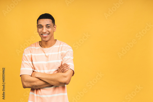 Portrait of a cheerful smiling young african american man standing isolated over yellow background.