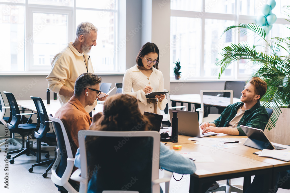 Creative male and female designers discussing paperwork and informative ideas for development startup project during collaboration in office workspace, professional people with modern technology