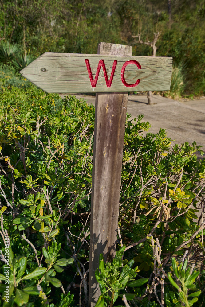 A rustic wooden sign pointing the way to the restroom