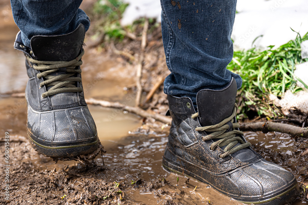 A man in jeans and boots walks through the swamp in rainy weather.