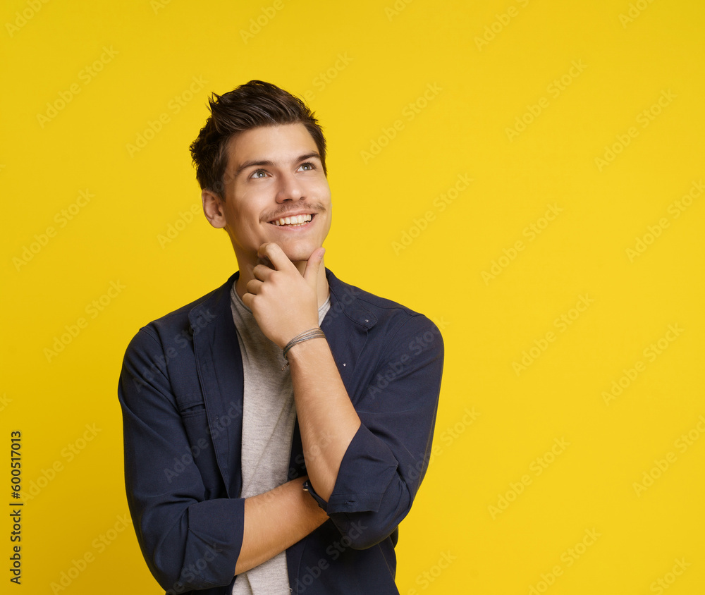 Young man in a thoughtful pose, with smile on his face, lost in his dreams and aspirations. Shot on yellow background, conveys sense of creativity and inspiration, highlighting his unique Young man in a thoughtful pose, with smile on his face, lost in his dreams and aspirations. Shot on yellow background, conveys sense of creativity and inspiration, highlighting his unique