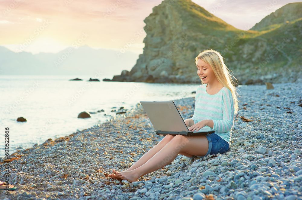 Technology and travel. Working outdoors. Freelance concept. Pretty young woman using laptop on the beach.
