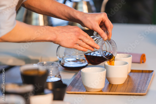 Barista pouring coffee in coffee cups.