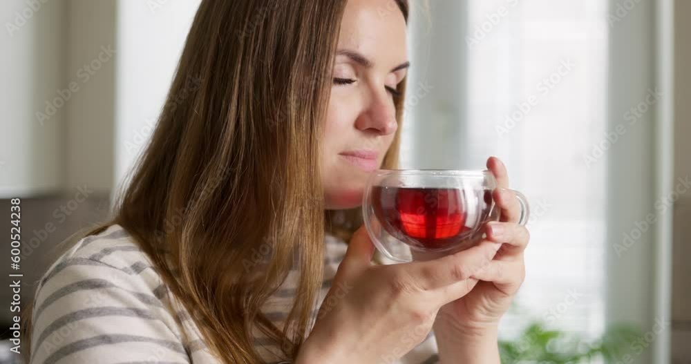A woman drinks her hot tea, enjoying the taste and aroma in the kitchen A woman drinks her hot tea, enjoying the taste and aroma in the kitchen