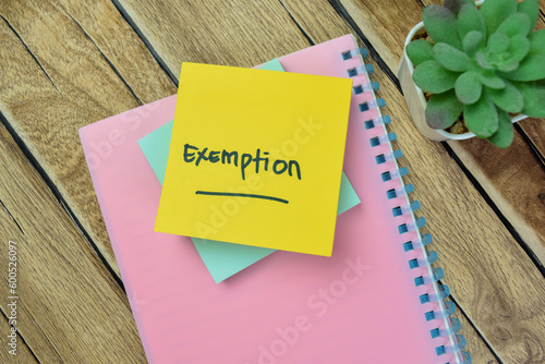 Concept of Exemption write on sticky notes isolated on Wooden Table. photo