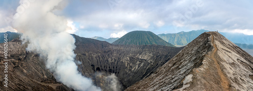 Hiking trail along the edge of Mount Bromo's crater with Mount Semeru, Mount Batok and the Sea of Sand (Segara Wedi) in the background, East, Java, Indonesia photo