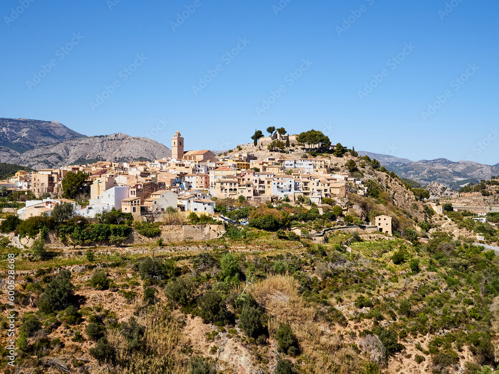 View of the church of San Pedro (St. Peter), the city wall, the houses and the castle on the hill in Polop de la Marina, a picturesque village in Marina Baixa, Alicante, Valencian Community, Spain