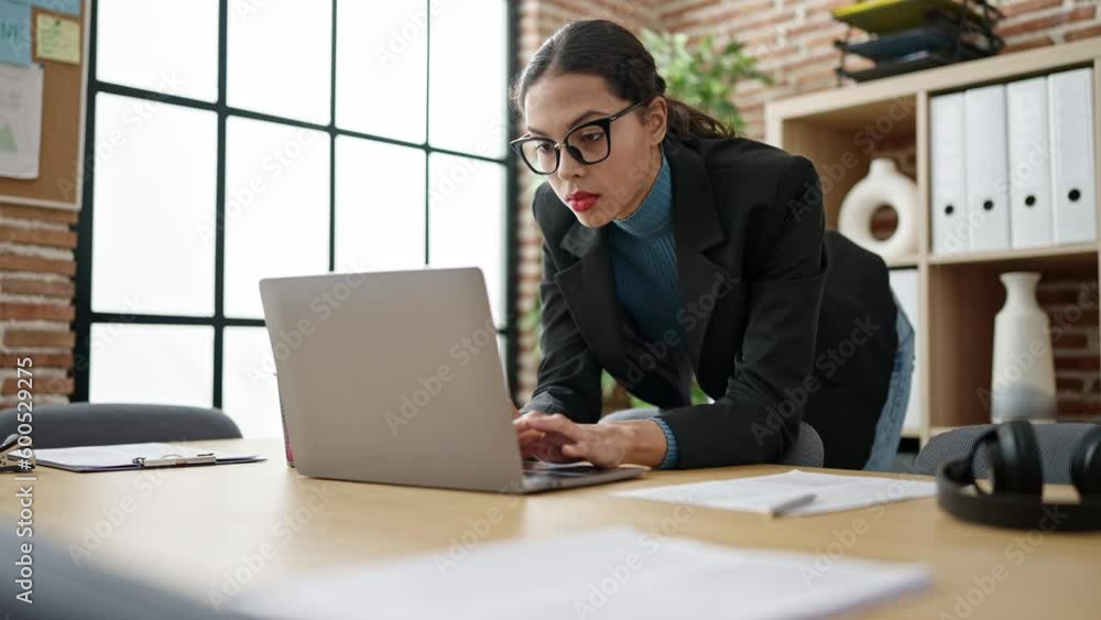 Young beautiful hispanic woman business worker using laptop standing at office Young beautiful hispanic woman business worker using laptop standing at office
