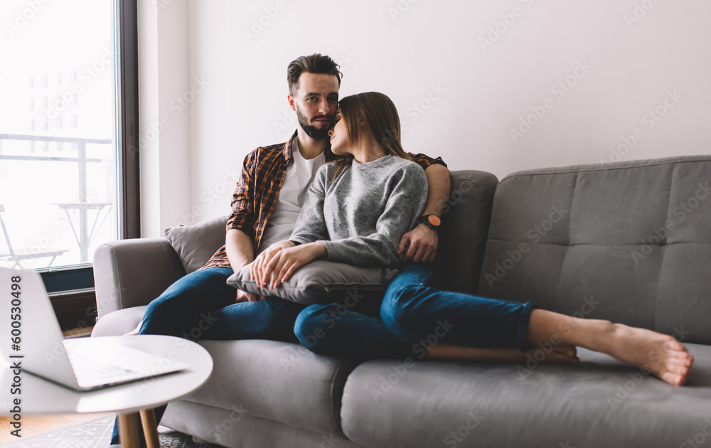 Portrait of man with woman 20s posing at home sofa spending free day togetherness, romantic Caucasian couple resting at comfortable couch looking at camera during leisure for family bonding
