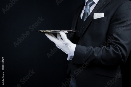Portrait of Elegant Butler or Waiter in Dark Suit and White Gloves Holding Silver Service Tray.