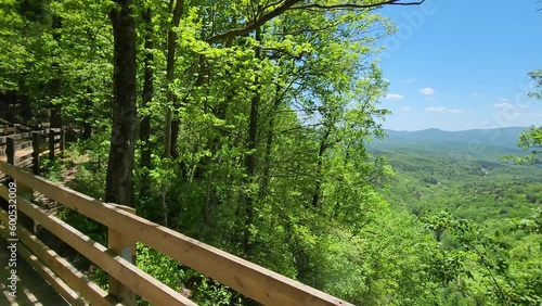 footage of a gorgeous spring landscape with a brown wooden fence,  lush green trees and plants, mountains, blue sky and clouds at Amicalola Falls State Park in Dawsonville Georgia USA photo