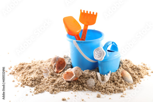 Toy bucket and shovel with sand and seashells isolated on white background photo