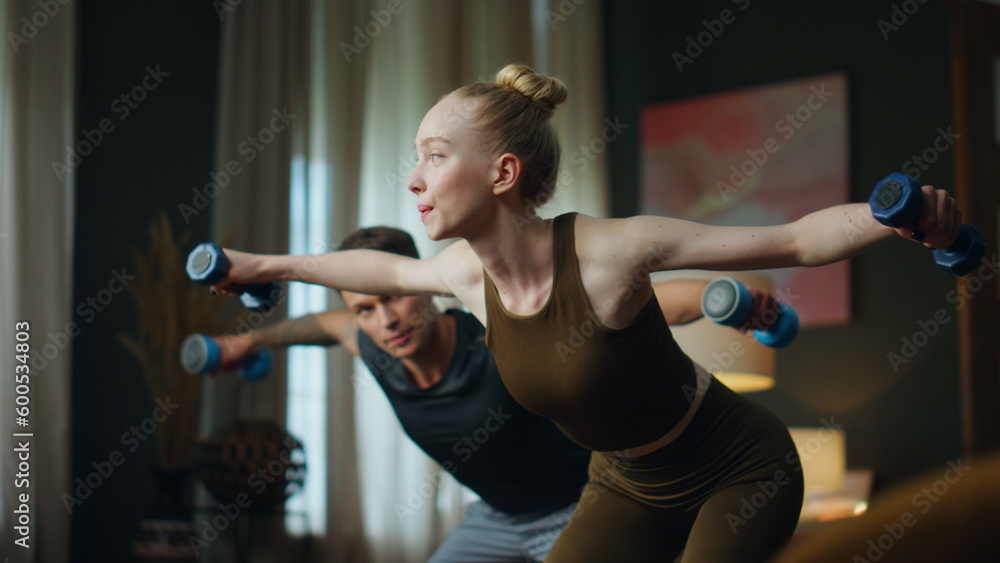 Family doing gym exercise with dumbbells at home. Couple training arms strength. Family doing gym exercise with dumbbells at home. Couple training arms strength.