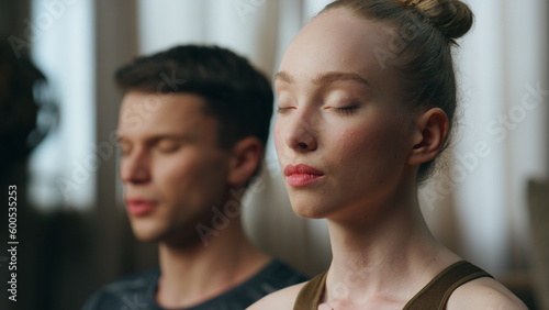 Portrait calm meditating couple with closed eyes close up. Pair practicing yoga.