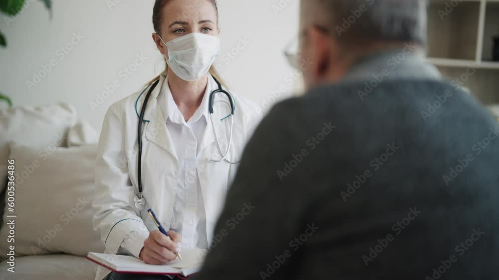 Woman doctor geriatric in medical mask holding notepad consulting senior man in clinic. Medical practitioner ask questions, filling patient disease history form, provide help, prescribe treatment. Woman doctor geriatric in medical mask holding notepad consulting senior man in clinic. Medical practitioner ask questions, filling patient disease history form, provide help, prescribe treatment.