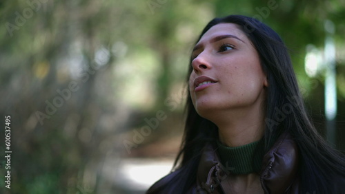 One pensive young woman walking outside at park during sunny day. Closeup face of a thoughtful person with contemplative expression