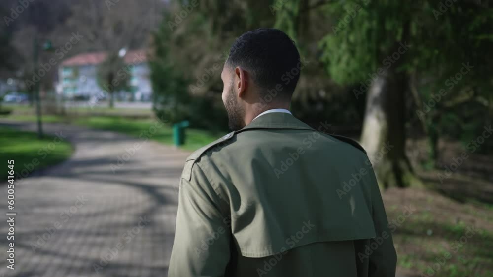 Back of person walking outside at park enjoying sunlight and fresh air. One young Arab Middle Eastern man taking a stroll Back of person walking outside at park enjoying sunlight and fresh air. One young Arab Middle Eastern man taking a stroll