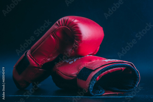 two red boxing gloves lie on a black background, combat sport