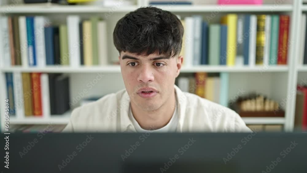 Young hispanic man student stressed using computer studying at library university Young hispanic man student stressed using computer studying at library university