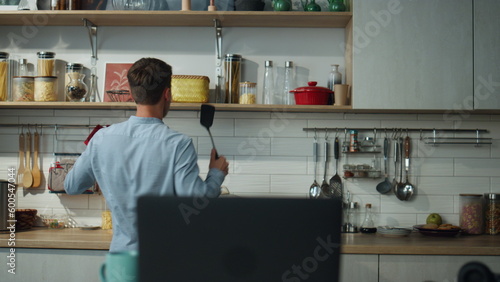 Man dancing cooking alone on kitchen with laptop. Chef guy preparing breakfast. © stockbusters