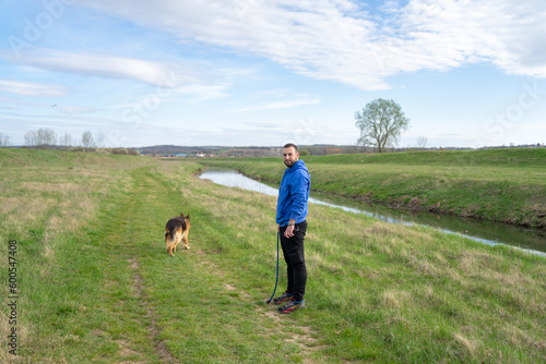 Young Man Walking His Dog in Meadow