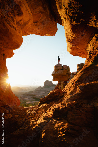 Tableau sur toile Vertical image woman standing at dramatic viewpoint of Merry-go-round Rock in Sedona Arizona admiring the golden orange sunset view
