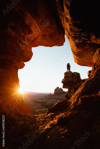 Young couple hugs at popular viewpoint rock formation in Sedona Arizona at golden orange sunset.