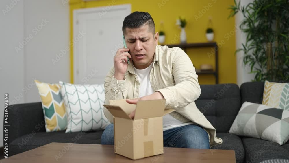 Young hispanic man speaking on the phone unpacking cardboard box at home Young hispanic man speaking on the phone unpacking cardboard box at home