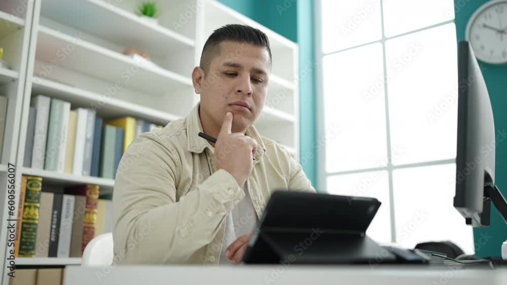 Young hispanic man student using touchpad studying at library university Young hispanic man student using touchpad studying at library university