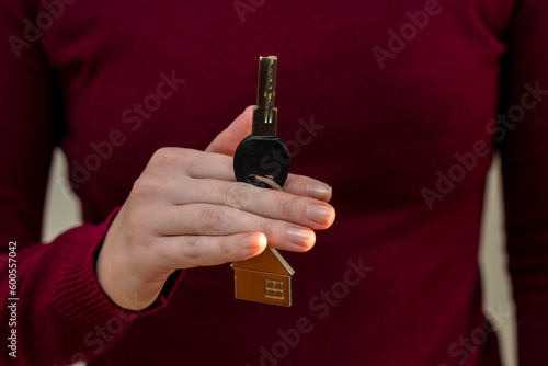 Woman's hands holding key with keychain in shape of the house
