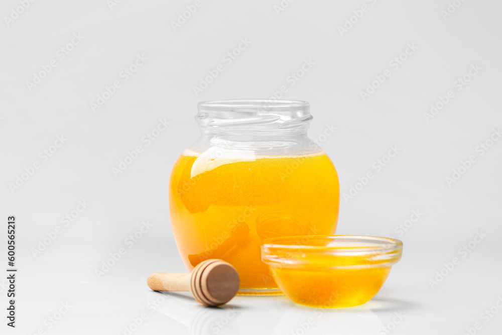 Honey in a jar with a wooden dipper on a white isolated background. Honey in a jar with a wooden dipper on a white isolated background.