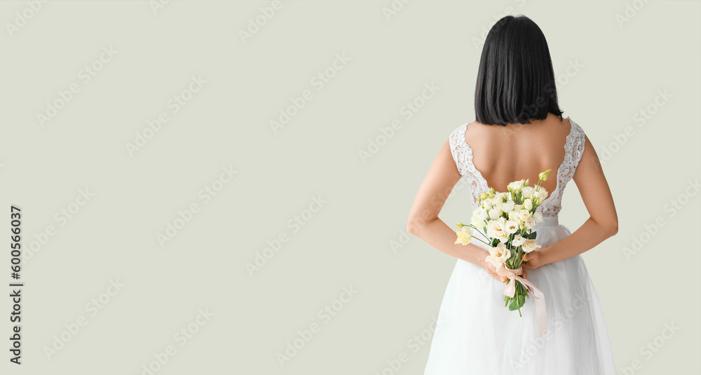 Beautiful young Asian bride with bouquet of eustoma flowers on light background with space for text, back view Beautiful young Asian bride with bouquet of eustoma flowers on light background with space for text, back view