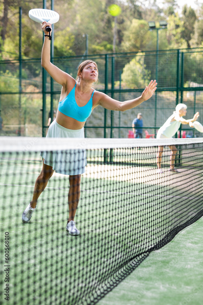 Attractive woman padel tennis player training on court. Young woman using racket to hit ball.
