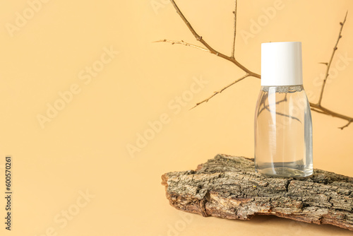 Bottle of micellar water with tree branch and bark on beige background