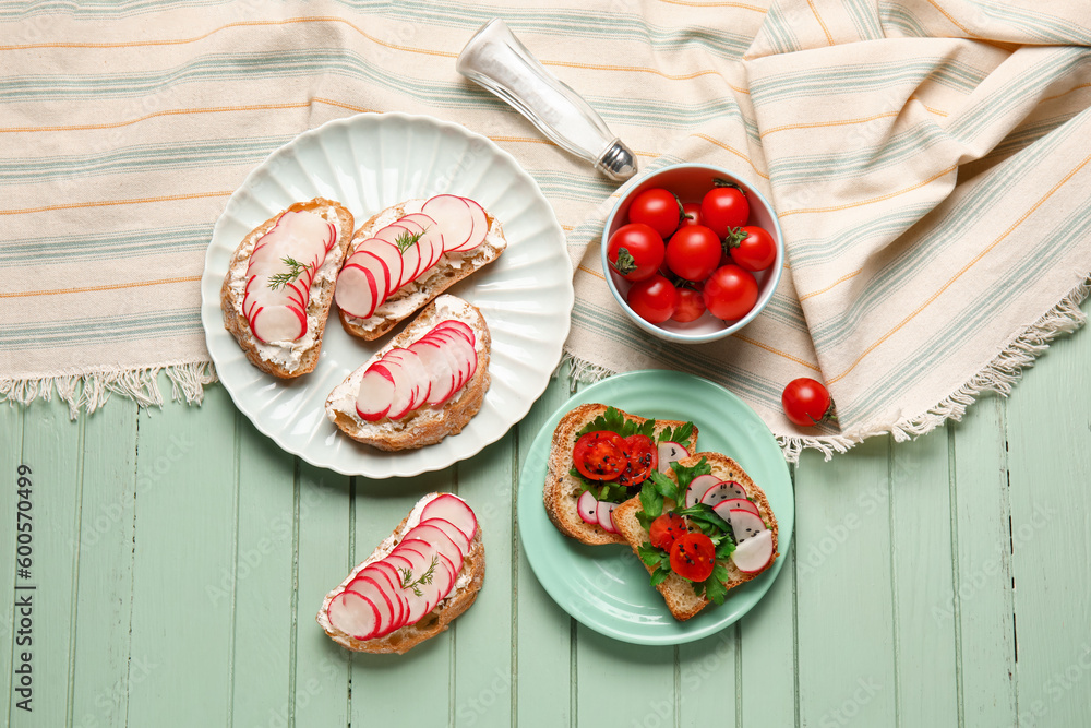 Plates with delicious radish bruschettas on green wooden table