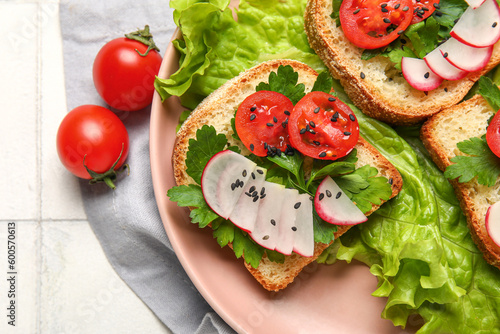 Plate with delicious radish bruschettas on white tiled table, closeup