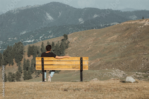 Boy sitting on a bench on a high mountain enjoy scene