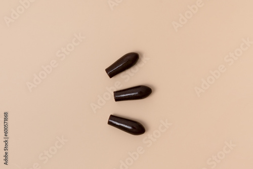 Group of brown rectal suppositories for anal or vaginal use on beige isolated background. Pills for alternative medicine, lowering temperature, hemorrhoids and wellness