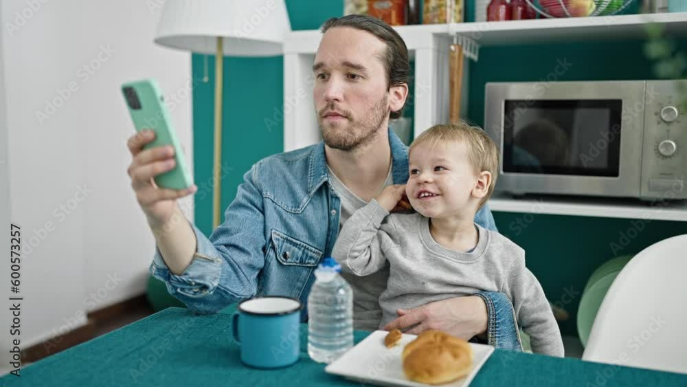 Father and son having breakfast using smartphone at dinning room Father and son having breakfast using smartphone at dinning room