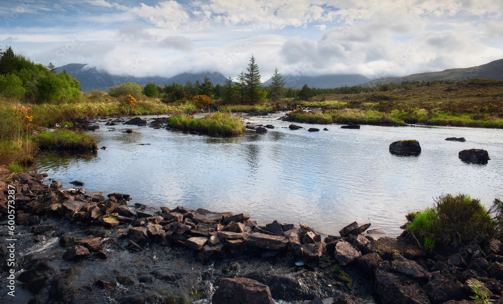 Beautiful landscape scenery with river stream, pine trees and mountains in the background at Derryclare natural reserve in Connemara National park, county Galway, Ireland 