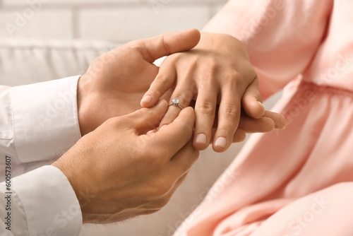 Fototapeta Naklejka Na Ścianę i Meble -  Man putting engagement ring on woman's finger, closeup