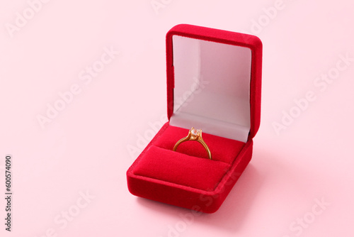 Box with engagement ring on pink background